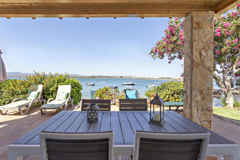 a wooden table and chairs on a deck with a view of the ocean at Villa Lydia in Faro
