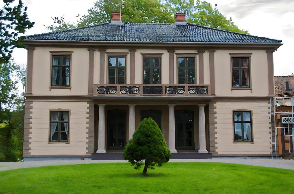 a large house with a tree in front of it at Frogner Hovedgård in Skien