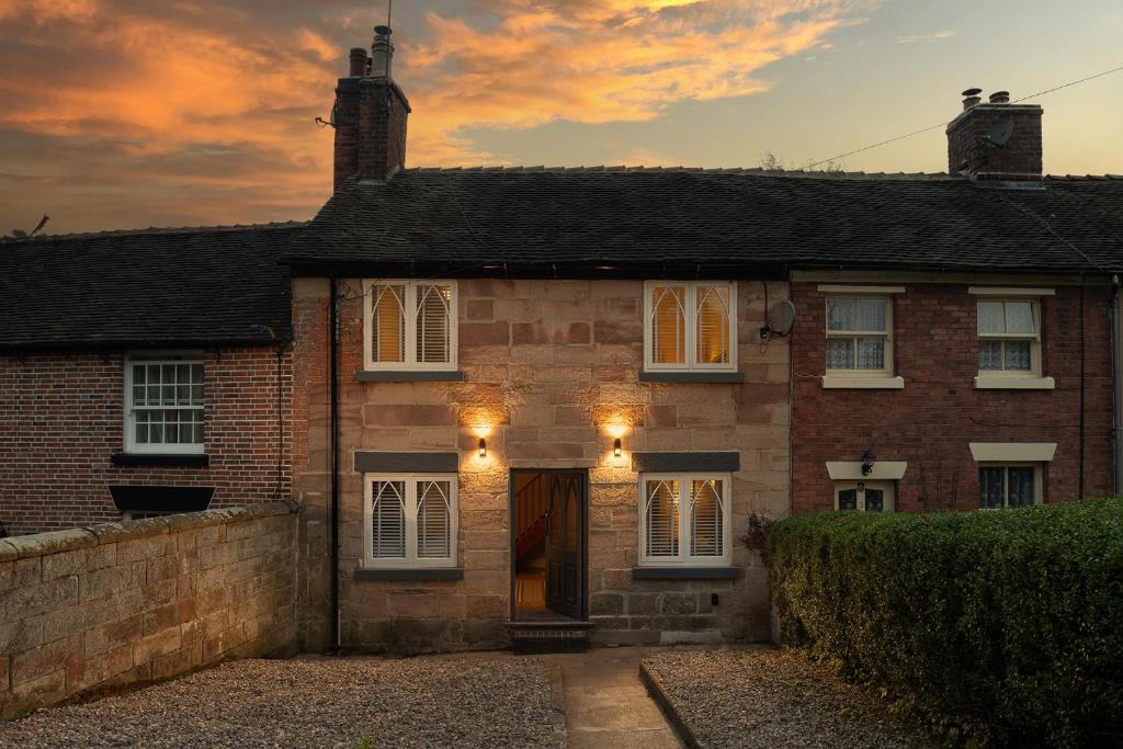 a brick house with a sunset in the background at Angel Cottage - 5 mins drive to Alton Towers! in Alton