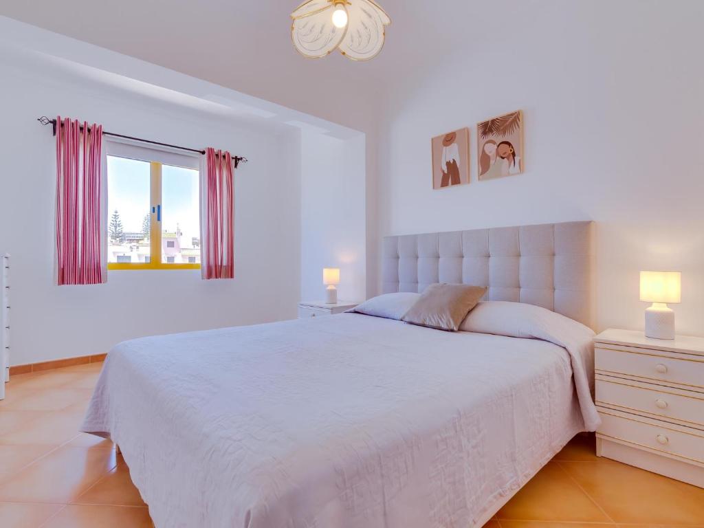 a white bedroom with a large bed and a window at AL - Apartamento Quinta do Romão in Quarteira