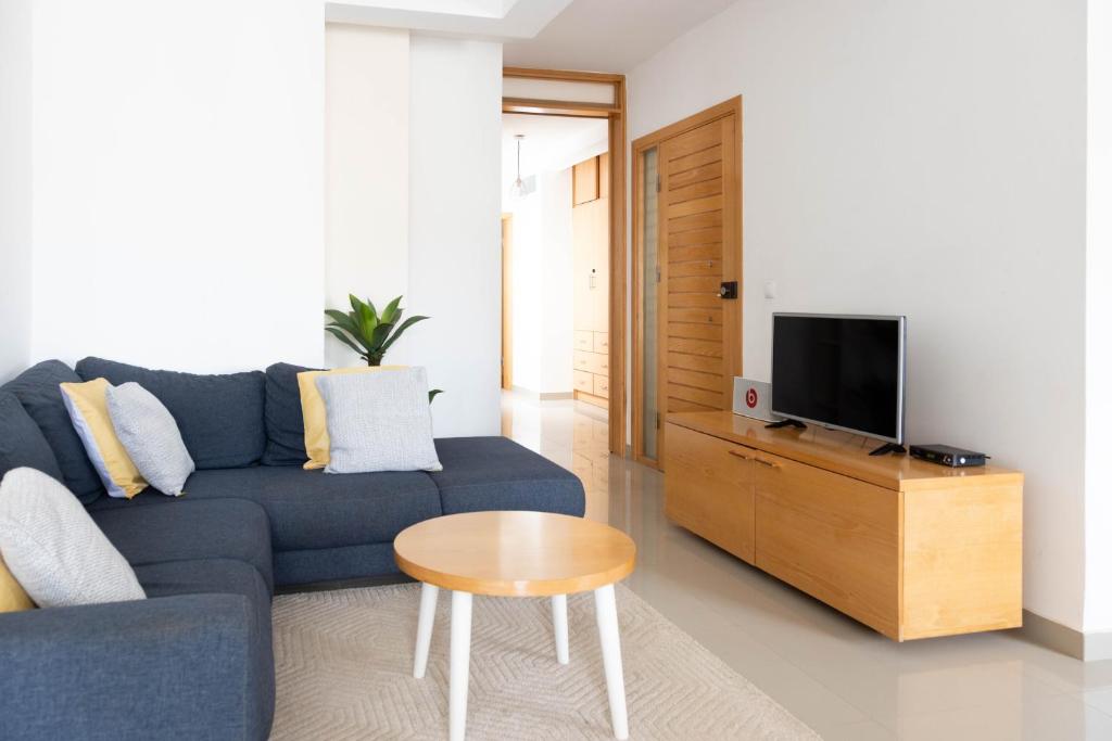 プライアにある2 bdr cozy apt near Praça Center, AC & Fast Wi-Fiの青いソファとテレビのあるリビングルーム