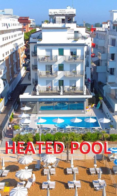 a large white building with umbrellas and a heated pool at Hotel El Salvador Frontemare Piscina Riscaldata in Lido di Jesolo