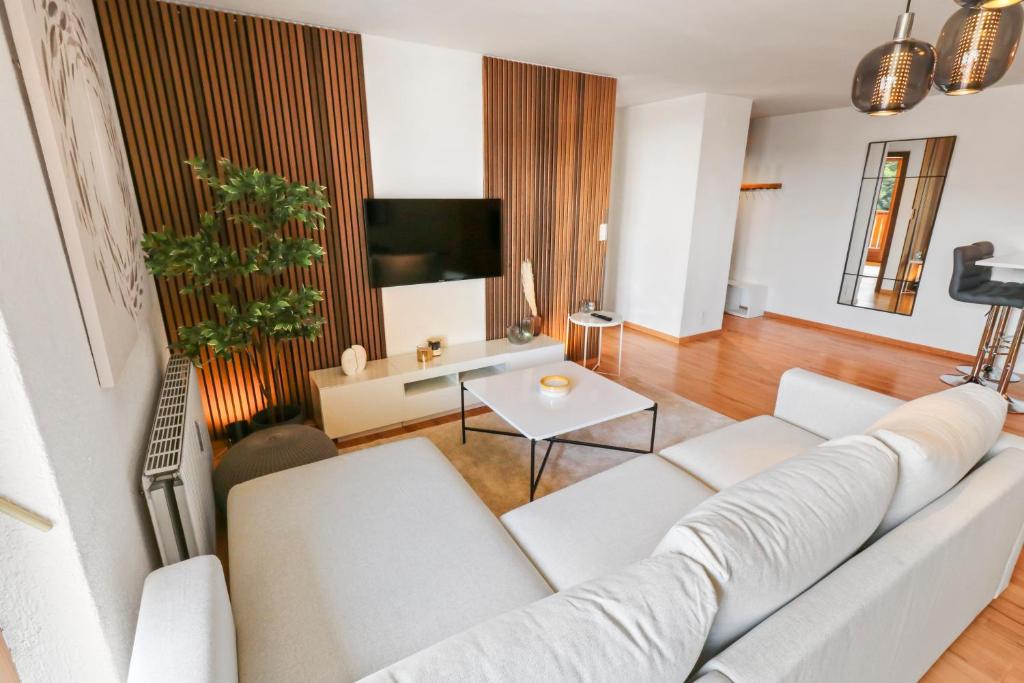 a living room with a white couch and a tv at Logement chaleureux au coeur de la station in Crans-Montana