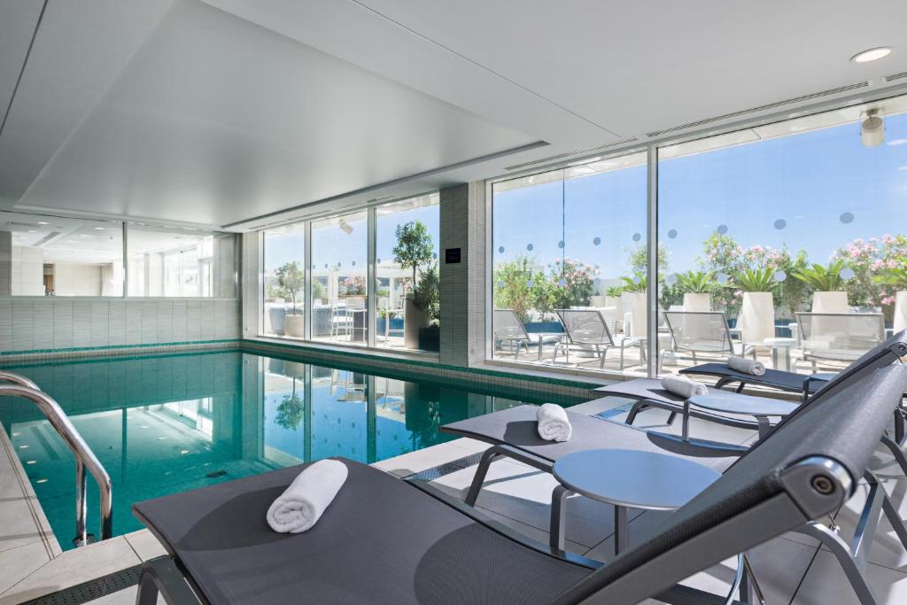 a swimming pool with tables and chairs in a building at Golden Tulip Marseille Euromed in Marseille