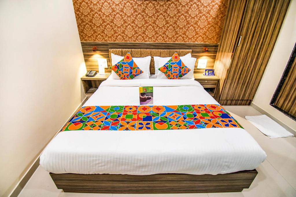 pokój hotelowy z łóżkiem z kolorowymi poduszkami w obiekcie FabExpress Orange Suite w Bombaju