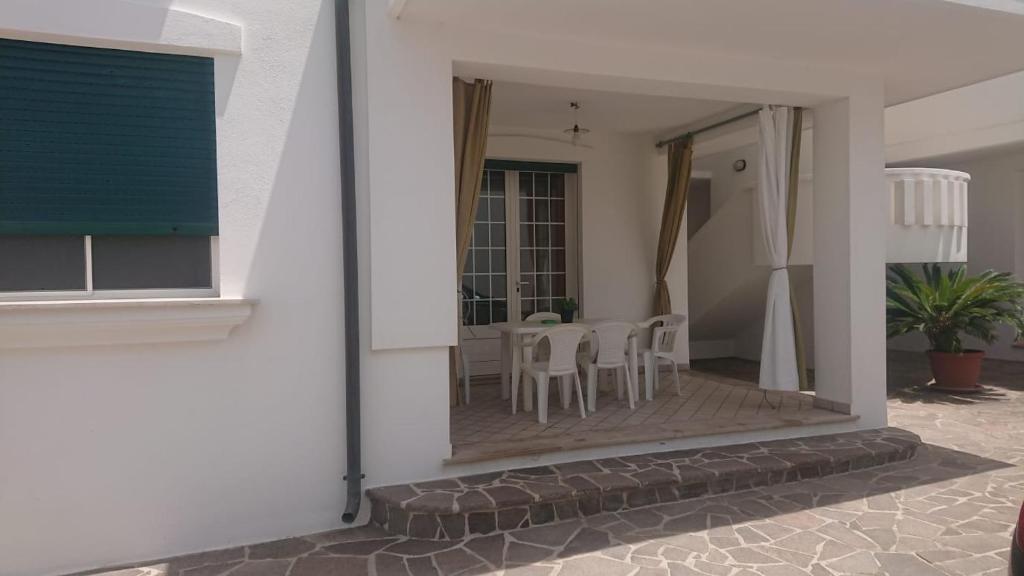una casa bianca con patio arredato con tavolo e sedie di CASA LEUCA a Leuca