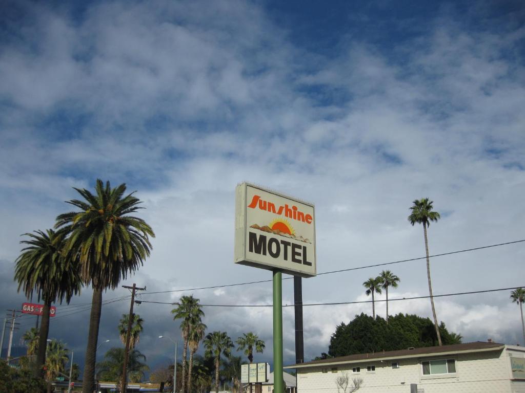 een motelbord voor een gebouw met palmbomen bij Sunshine Motel in San Bernardino