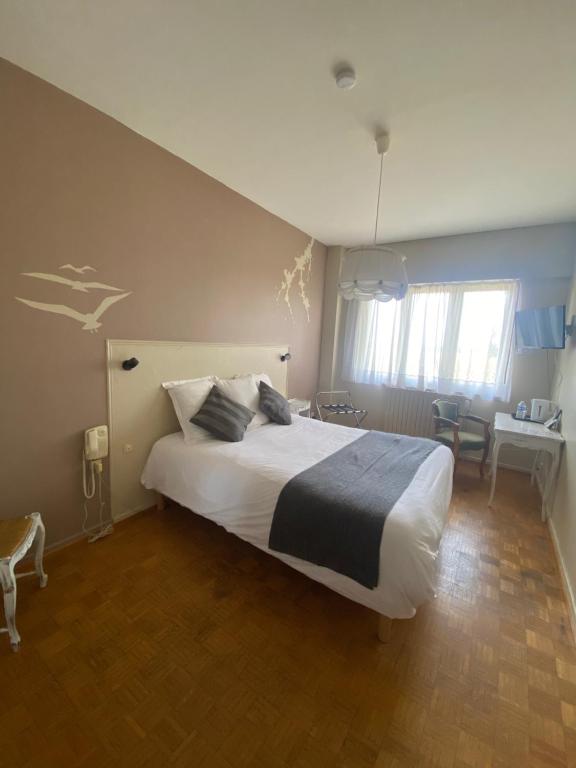 1 dormitorio con 1 cama grande y escritorio en Logis L'Auberge du Gros, en Silly-sur-Nied