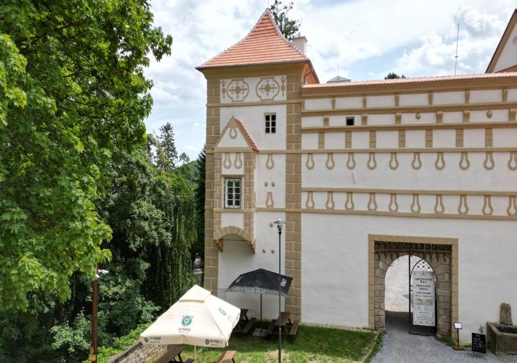 ein Gebäude mit einem Uhrturm mit einem Regenschirm in der Unterkunft Zámek Castle Račice - Předzámčí Forecastle in Račice