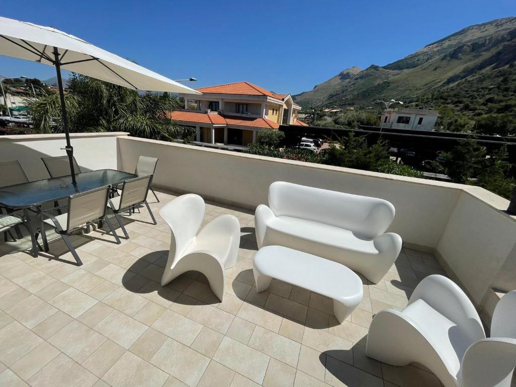 a patio with white chairs and a table and an umbrella at Martanna Rooms in Carini