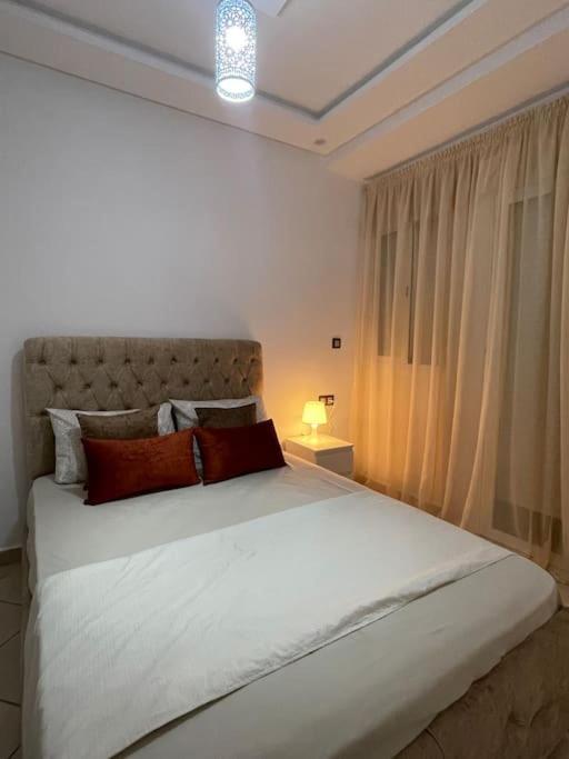 a bedroom with a large white bed and a window at Appartement de luxe a Rimal Martil 1 min de la plage in Martil