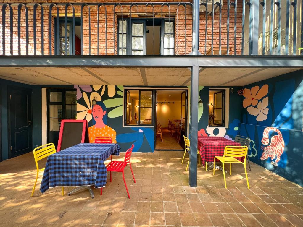 un patio con mesa, sillas y un mural en Black Tomato Hostel Kutaisi en Kutaisi