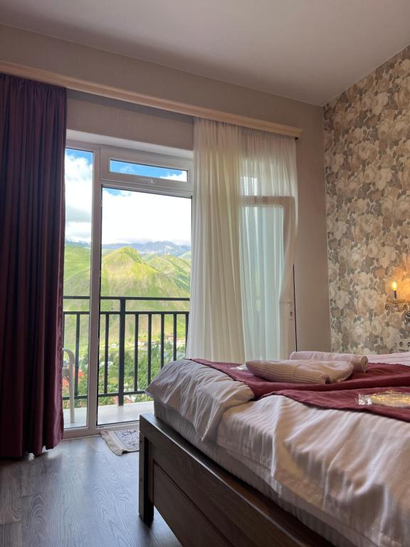 a bedroom with a bed and a large window at Planet kazbegi in Stepantsminda