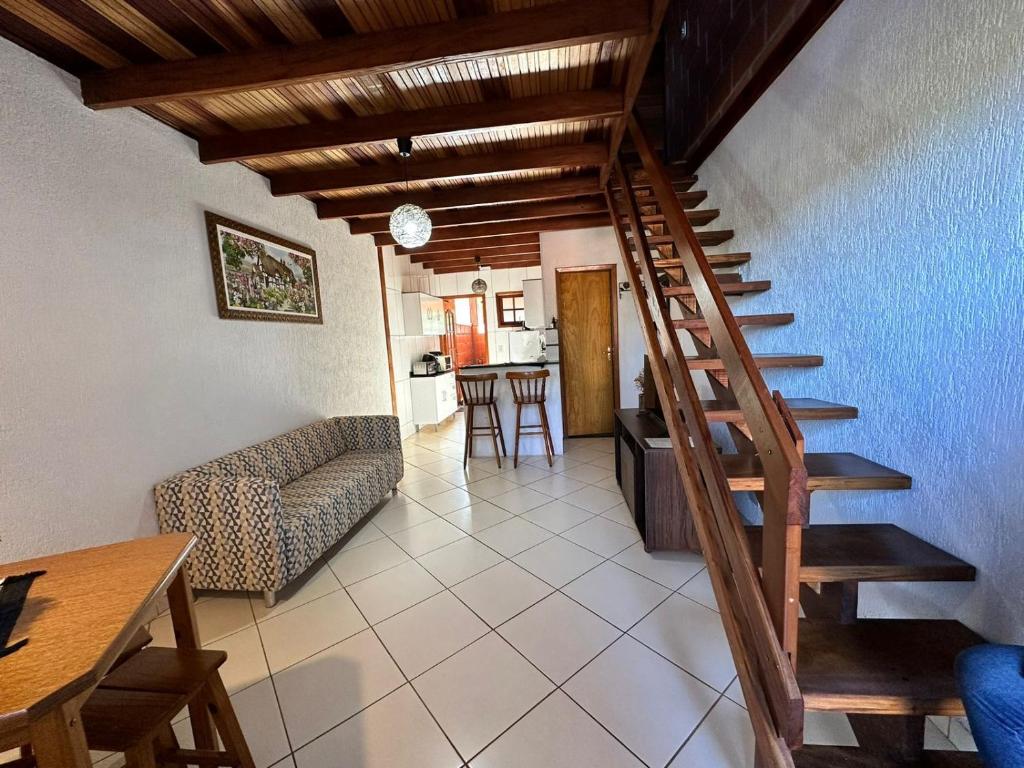 escalera en una sala de estar con sofá y mesa en Chalé da Lu, en Santo Antônio do Pinhal