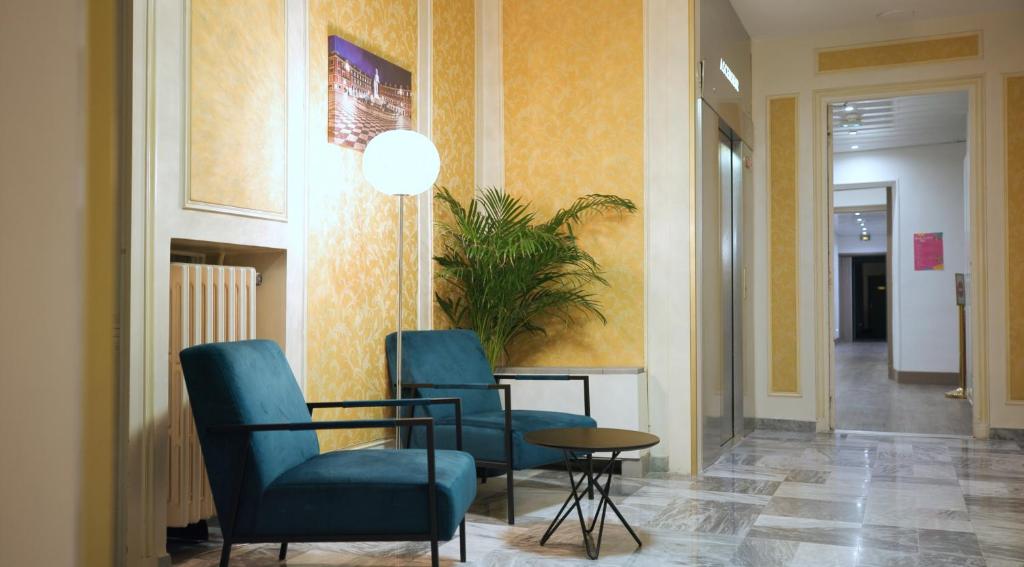 un pasillo con sillas azules y una mesa en una habitación en Hotel Busby, en Niza
