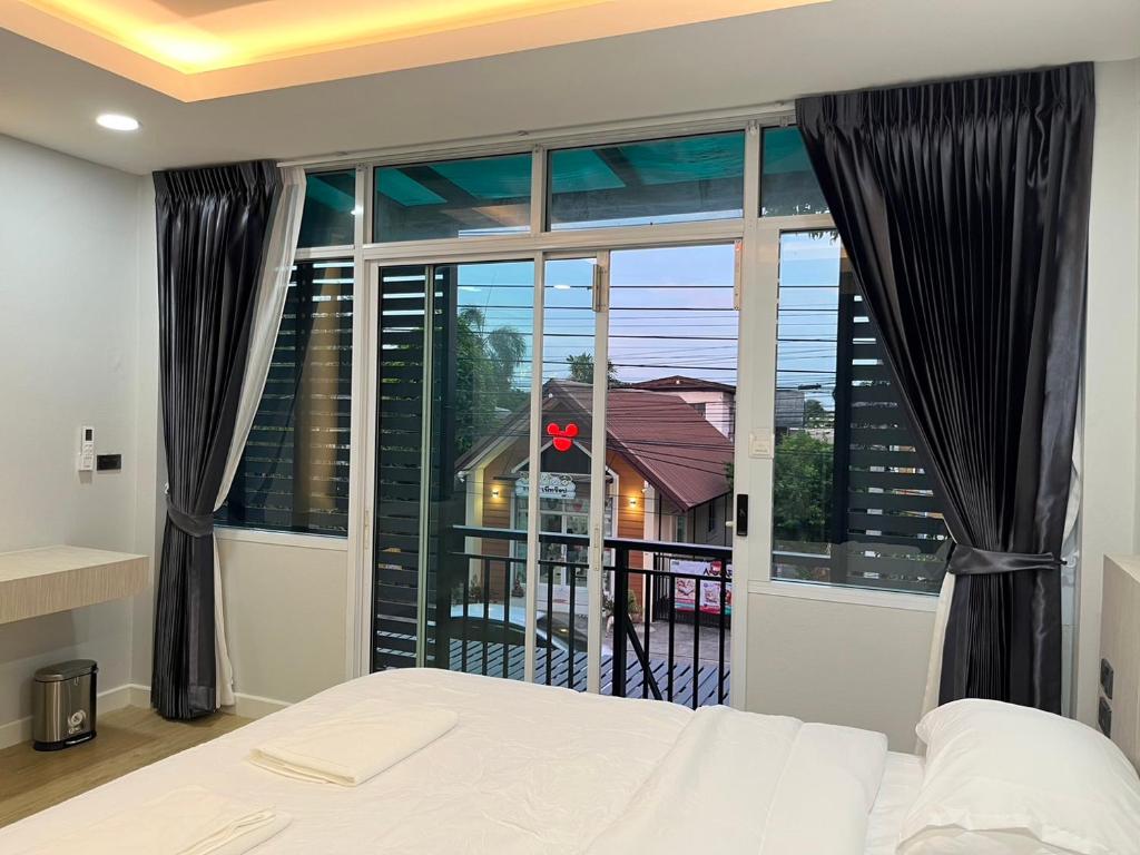 1 dormitorio con cama y ventana grande en The leaf mango tree, en Kamphaeng Phet