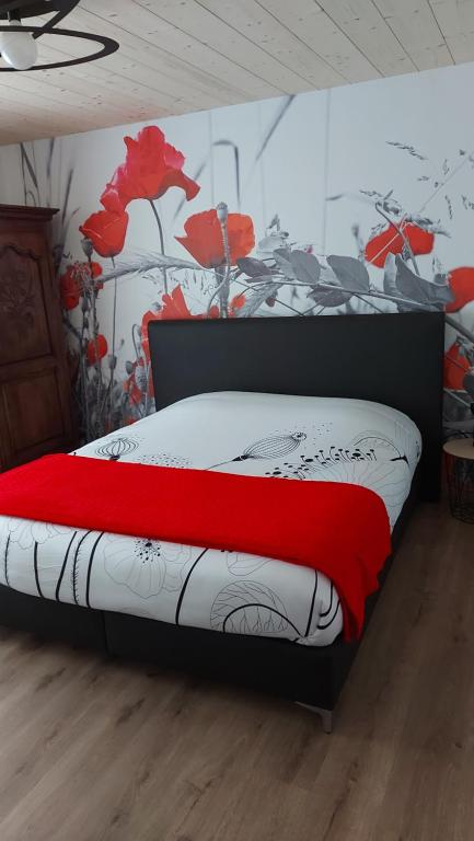 um quarto com uma cama com um cobertor vermelho em LE NID DES PLANCHETTES - Suite Chambres d'Hôtes 