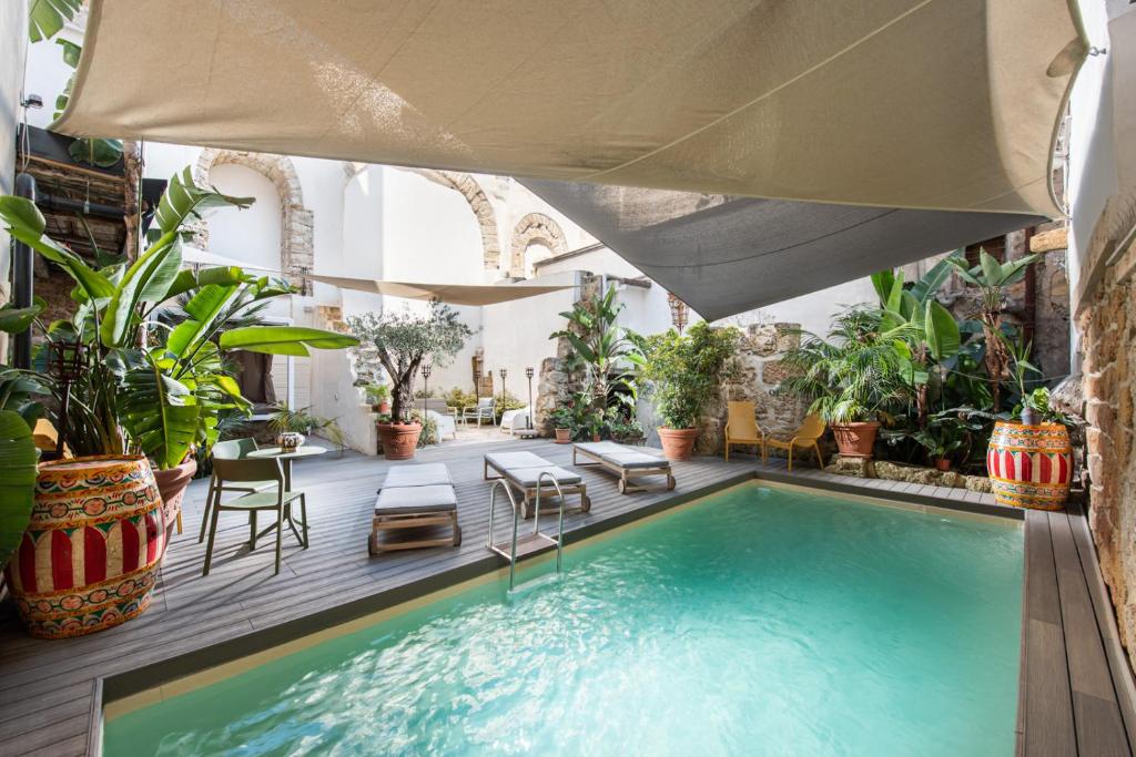 an indoor pool with plants and a large umbrella at Porta di Castro Boutique Hotel & SPA in Palermo