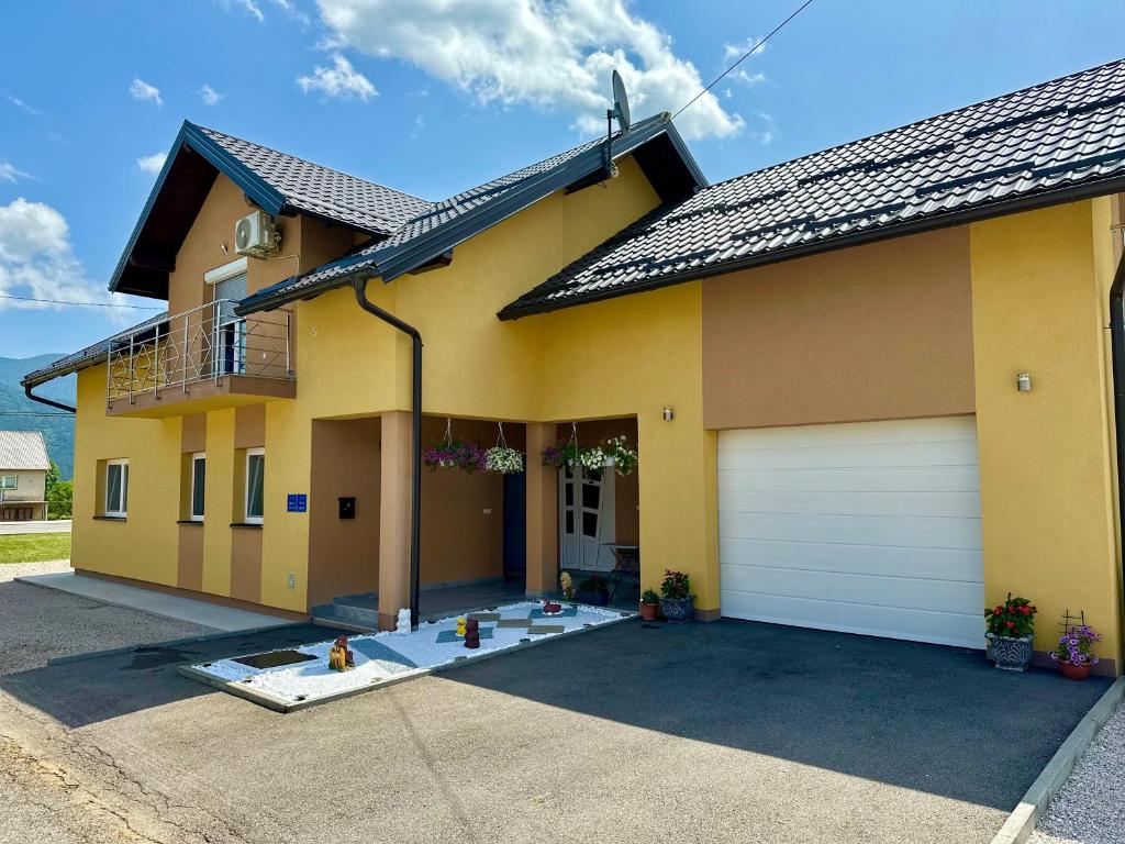 ein gelbes Haus mit einer weißen Garagentür in der Unterkunft Sweet Dreams Home in Korenica