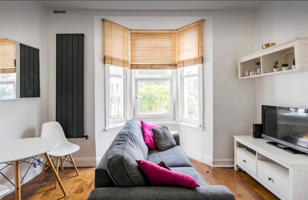 ein Wohnzimmer mit einem Sofa und einem TV in der Unterkunft Hill Herne Hill Duplex in London