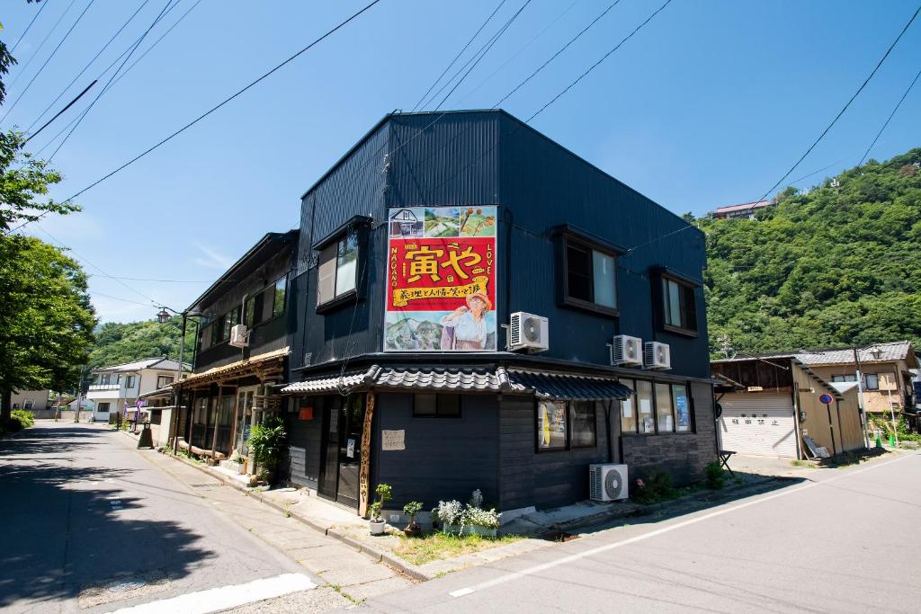 un edificio negro con un cartel en el costado en おせっかいゲストハウス 昭和の寅や en Chikuma