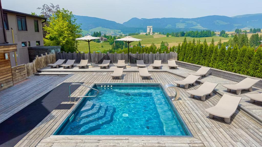 una piscina con sedie a sdraio e un mucchio di cose di Linta Hotel Wellness & Spa ad Asiago