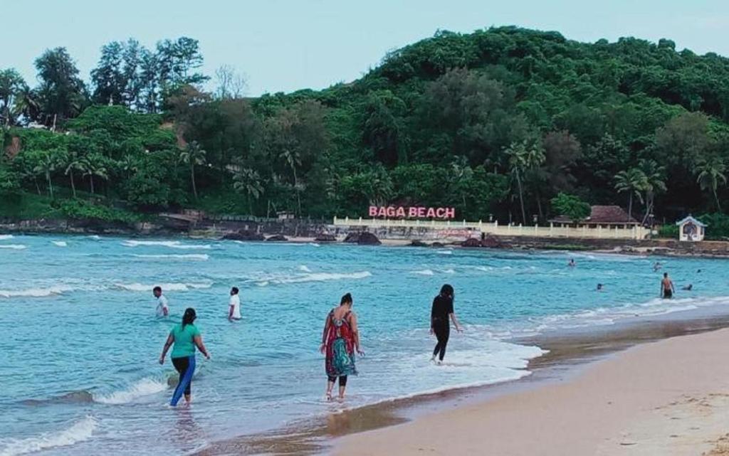 a group of people walking in the water on a beach at Baga Beach Way in Baga