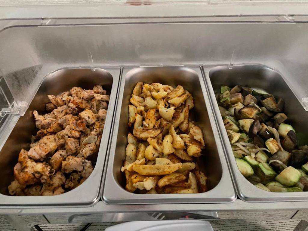 three metal trays of food in a refrigerator at Reikartz Amirun Tashkent in Tashkent