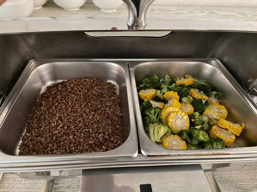 a metal tray of food with broccoli and other foods at Reikartz Amirun Tashkent in Tashkent