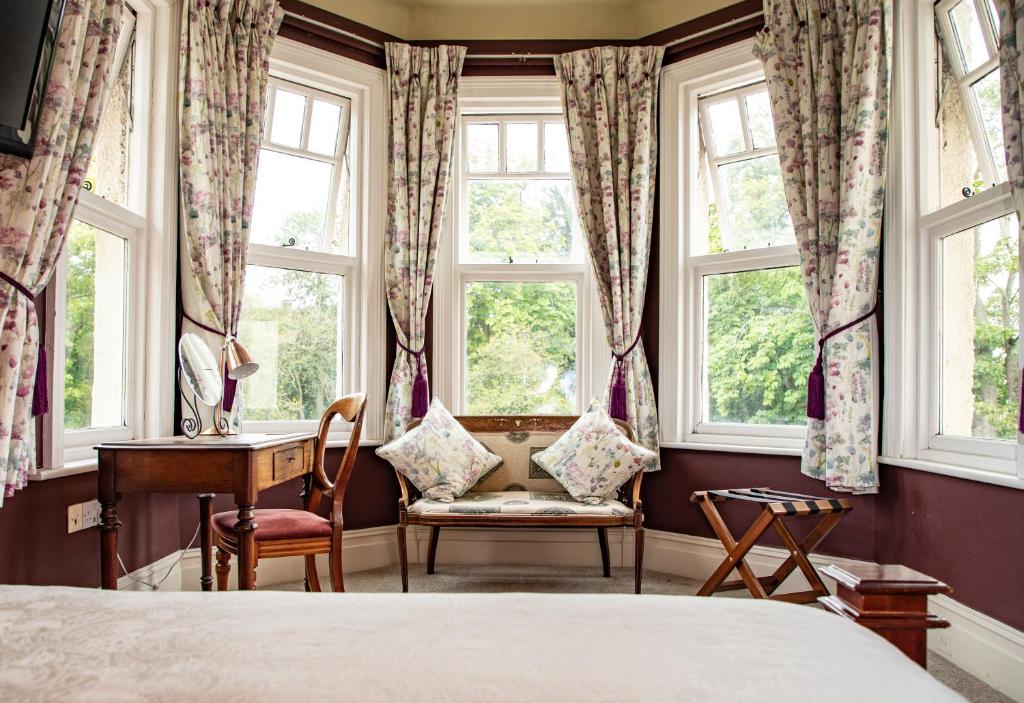 a bedroom with a bed and a desk and windows at Mere Brook House in Wirral