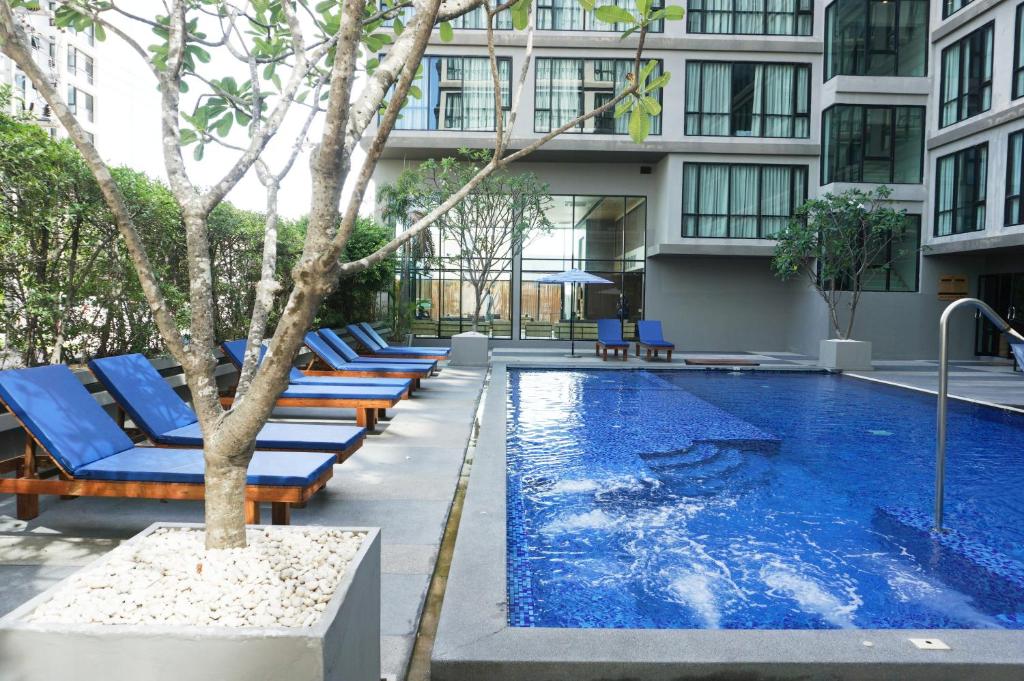 a pool with blue lounge chairs next to a building at Beston Pattaya - SHA Plus Certified in Pattaya South