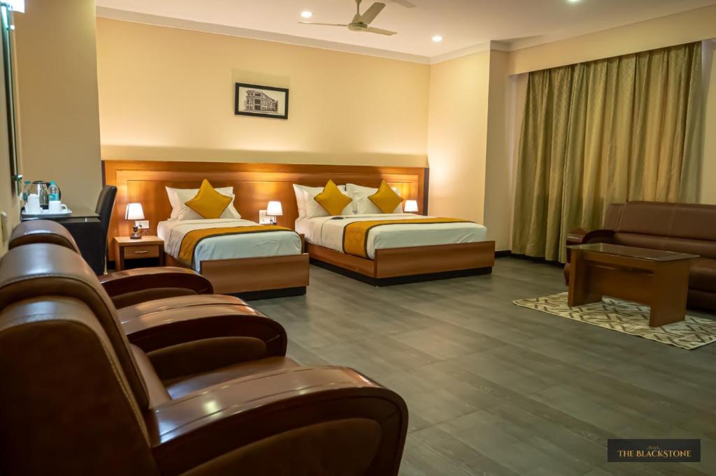 a hotel room with two beds and a couch at Hotel The Black Stone in Bangalore