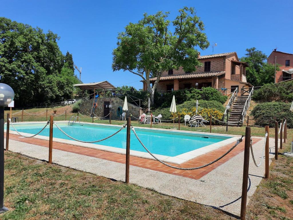 a swimming pool with a hammock in front of a house at Agriturismo Podere Valdilucciole in Città della Pieve