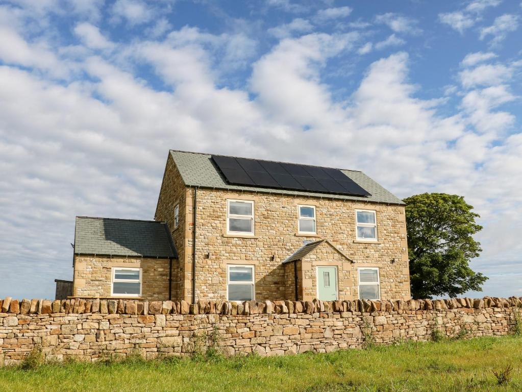 a house with solar panels on top of a stone wall at Forestside View in Bishop Auckland