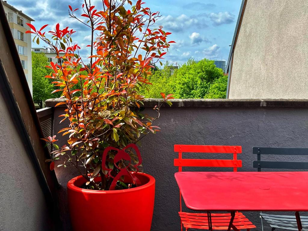 uma planta vermelha num pote vermelho ao lado de uma cadeira vermelha em Le Balcon fleuri centre Robertsau tram Jardiniers em Estrasburgo