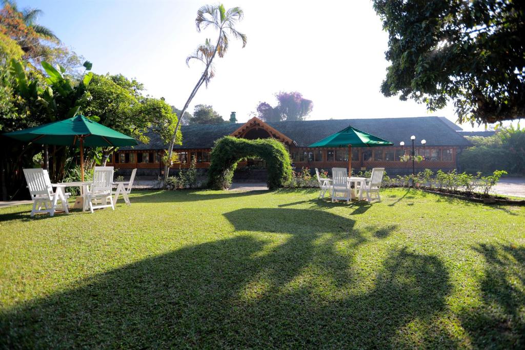 einen Garten mit weißen Stühlen, einem Bogen und einem Haus in der Unterkunft Bandarawela Hotel in Bandarawela