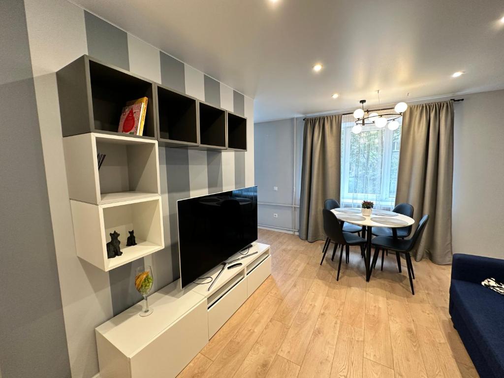 a living room with a television and a dining room table at Parkside Escape: Stylish 1-BR in Rīga