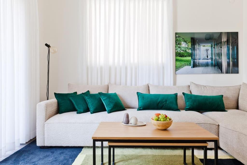 a living room with a white couch with green pillows at Designed 2BR apartment over Dizengoff square - Panoramic View in Tel Aviv