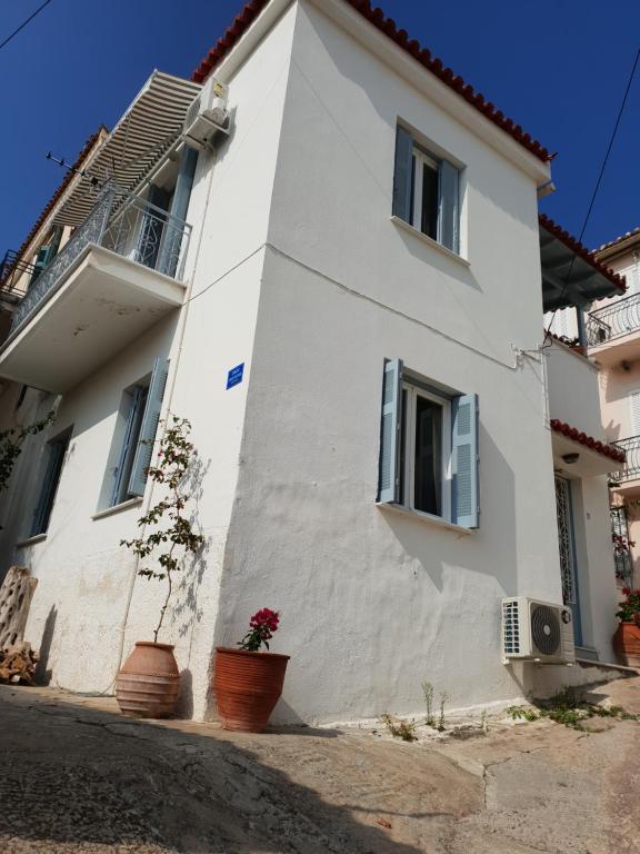 ein weißes Haus mit Topfpflanzen davor in der Unterkunft ISLAND HOUSE in Poros