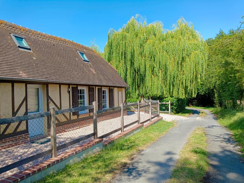 a house with a fence next to a road at Gîte Les Mirabelles Calme et Reposant in Vieux-Pont-En-Auge