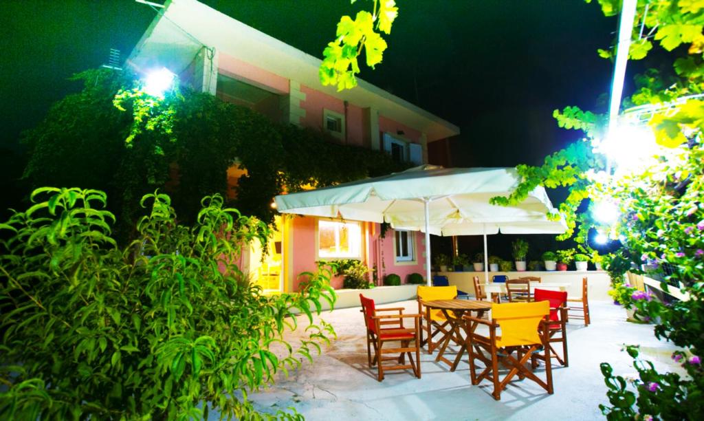 eine Terrasse mit einem Tisch mit Stühlen und einem Sonnenschirm in der Unterkunft BABI'S VILLA - Garden apartment in Lixouri
