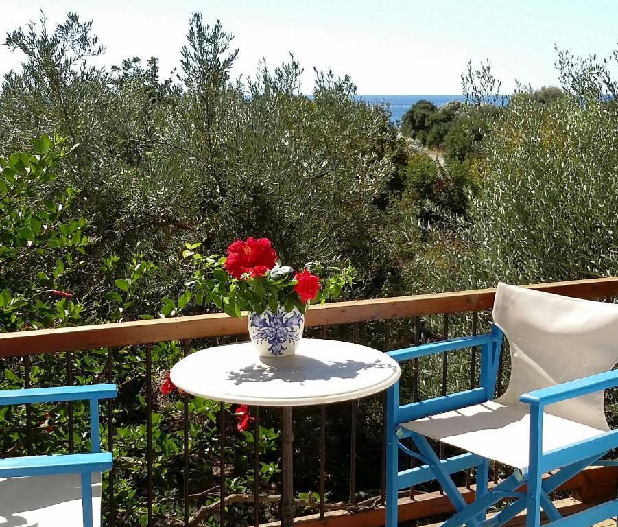 una mesa y 2 sillas y un jarrón de flores en el balcón en Olive tree Cottages, en Palaiochóra