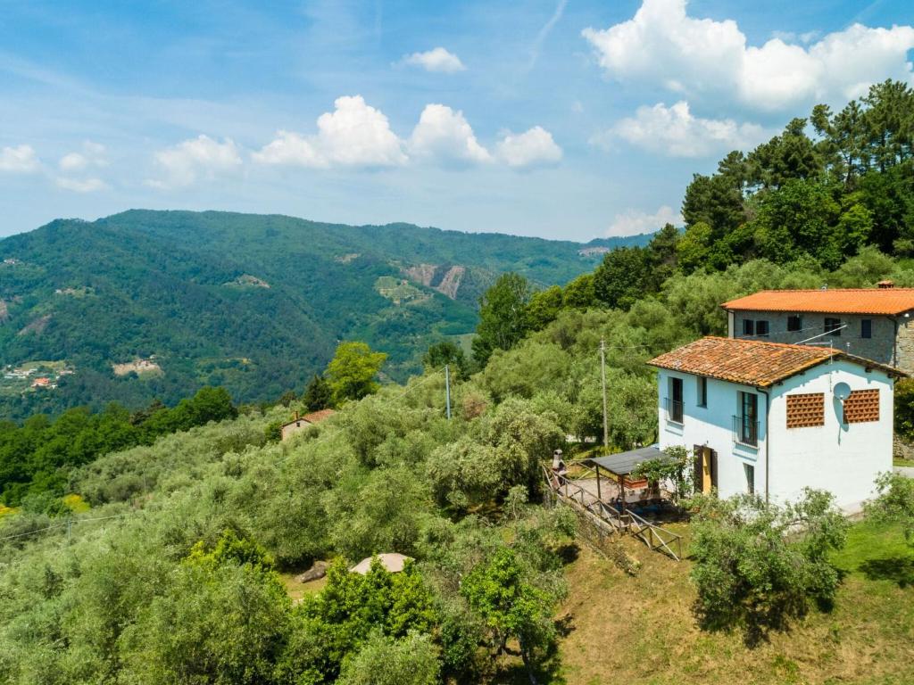 uma casa numa colina com montanhas ao fundo em Idyllic Holiday Home in Pescia with Swimming Pool em Uzzano