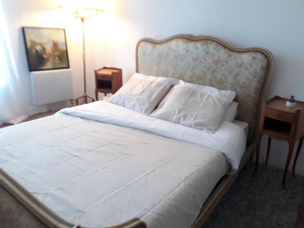 1 dormitorio con 1 cama con sábanas y almohadas blancas en La Marginale, en Fontevraud-l'Abbaye