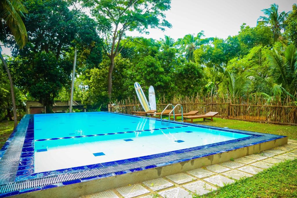 - une piscine dans une cour avec 2 planches de surf dans l'établissement Talalla Freedom Resort, à Talalla South