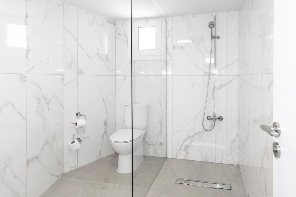 a white bathroom with a shower and a toilet at Blazer Residence in Larnaka