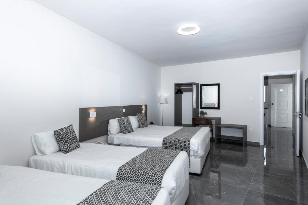 a hotel room with two beds and a couch at Blazer Residence in Larnaka