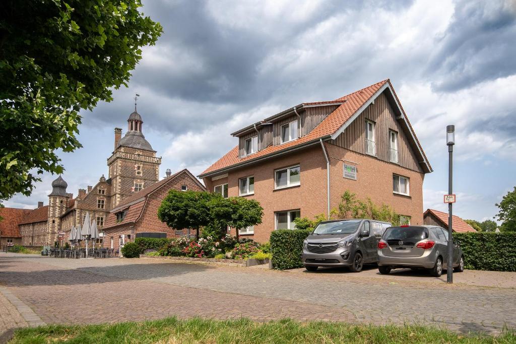 zwei Autos auf einem Parkplatz vor einem Gebäude geparkt in der Unterkunft Hotel am Tiergarten in Raesfeld