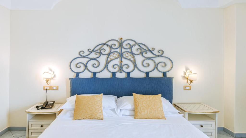 a bedroom with a large bed with a blue headboard at Hotel Nettuno in Ischia