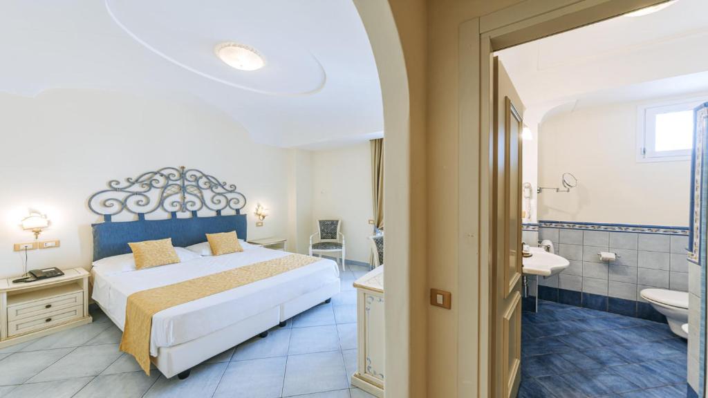 a bedroom with a large bed and a bathroom at Hotel Nettuno in Ischia